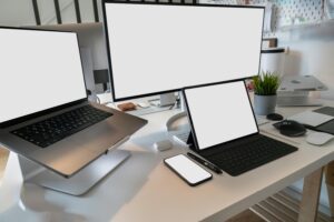 A clean and modern workspace featuring a laptop, tablet, smartphone, and monitor. Ideal for remote work and tech setups.