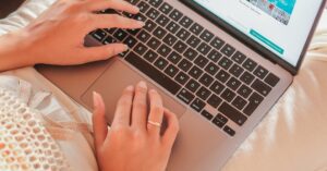 A woman comfortably working on a laptop from home, showcasing remote work lifestyle.